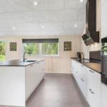 Modern kitchen with island, white cabinets, and dark worktops.
