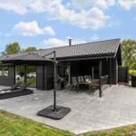 Modern villa with large patio, grill, loungers, and hot tub in the garden.