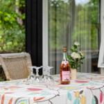 Table with floral tablecloth, wine bottle, and glasses outdoors.