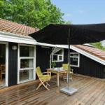 Deck with table, two chairs, and umbrella in front of a house with wooden porch.
