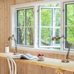Schreibtisch mit Stuhl, Lampe und Blick auf Wald