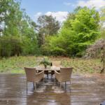Terrasse mit Tisch und Stühlen, Blick in einen grünen Wald.