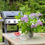 Gartenbereich mit Grill, Tisch, Stühlen und Blumenstrauß.