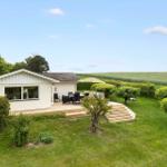 A house with terrace, garden, and view of fields.