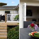 Deck with umbrella and lounge chairs. House in background. Table with watermelon and flowers.