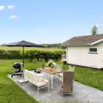 Terrace with table, chairs, umbrella, and grill. Lawn and house in the background.