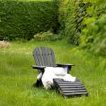 A black lounge chair with a white blanket in the green garden.