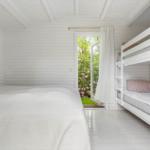 Room with double bed and bunk bed, door to garden with flowers.