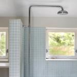 Shower cabin with blue tiles and two windows. Showerhead on the ceiling.