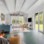 Living room with fireplace, sofa, TV, and terrace. Wooden floor and white walls.