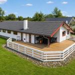 A house with a terrace, grill, and garden. White facade, red accents, and gray roof.