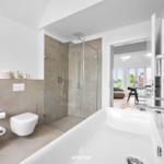 Badezimmer mit Dusche, Toilette und Badewanne. Durchgang zum Wohnbereich.