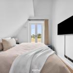 Schlafzimmer mit Bett, TV und Fenster zur Außenseite.