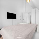 Schlafzimmer mit Bett, Fernseher und Kleiderschrank unter Dachschräge.