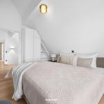 Schlafzimmer mit Bett, Nachttischen und Schrank unter Dachschrägen.