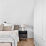 Schlafzimmer mit Bett, Nachttisch und Kleiderschrank. Holzdielenboden und weiße Wände.