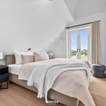 Schlafzimmer mit Dachschrägen, Bett, Nachttisch, Fenster und Fernseher.