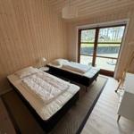 Two beds in a room with wooden walls and a window to the outdoor area.