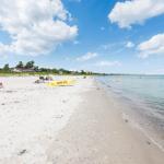 Beach with white sand and clear water, people relaxing and a rescue boat on the shore.