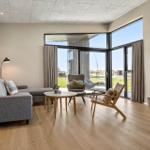 Living room with sofa, chairs, and large window to terrace.