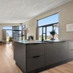 Kitchen with island and large window. Living area with sofa and table.