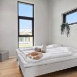 Bedroom with large window, bed, and plant on the wall.