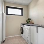 Laundry room with washing machine, dryer, and sink. Window and white cabinets.