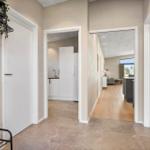 Hallway with view into kitchen and living room. Wooden and tile flooring.