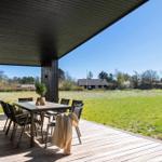 Patio with table and chairs, view of green field and sky.