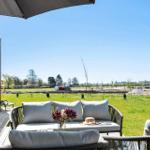 Terrace with seating and view of green field under clear sky.