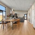 Dining area with wooden table and chairs. Kitchen and terrace are visible.