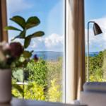 Through the window, you can see the sea and green trees.