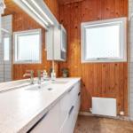 Bathroom with wooden wall, sink, and shower with glass enclosure.