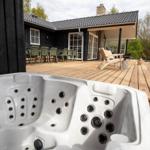 Hot tub on terrace with view of house and garden