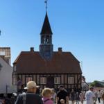 Historic building with tower and clock in a busy street with pedestrians.
