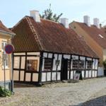 Traditional half-timbered house with red tiled roof and stone facade on a cobblestone street.