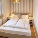 Schlafzimmer mit Doppelbett, zwei Nachttischen und Streifenwand
