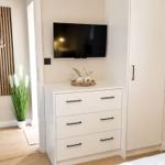 Schlafzimmer mit weißem Schrank, TV und Pflanze