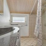 Badezimmer mit Dusche, Waschbecken und Toilette unter Holzdecke.