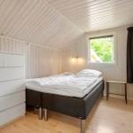 Schlafzimmer mit Bett, Schrank und Fenster. Holzwände und -decke.