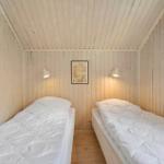 Zwei Betten in einem Zimmer mit Holzwandverkleidung und Deckenbalken.