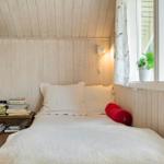 Schlafzimmer mit Bett, Bücherregal und Fenster mit Pflanze.