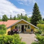 Ein gelbes Haus mit Terrasse und Garten. Möbel stehen draußen. Bäume umgeben das Grundstück.