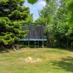 Hinterhof mit Trampolin und kleinem Feuer im Gras.