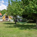Hängemattenschau in grünem Garten mit gelbem Haus und Baum