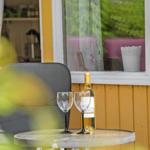 Ein Tisch mit Weinflasche und Gläsern vor einem Fenster mit Blick auf grüne Pflanzen.