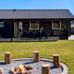 Haus mit Terrasse, Grill und Feuerstelle im Garten.