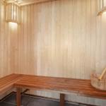 Sauna mit Holzwand, Sitzbank und Eimer mit Besen