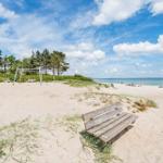 Holzbank auf Sandstrand mit Blick auf Meer und Strandbereich.