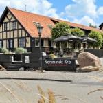 Norsminde Kro mit Terrasse, Sitzgelegenheiten und Steinbecken im Freien.